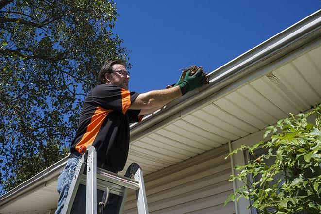 maintenance worker using a ladder to repair a gutter in Albion RI